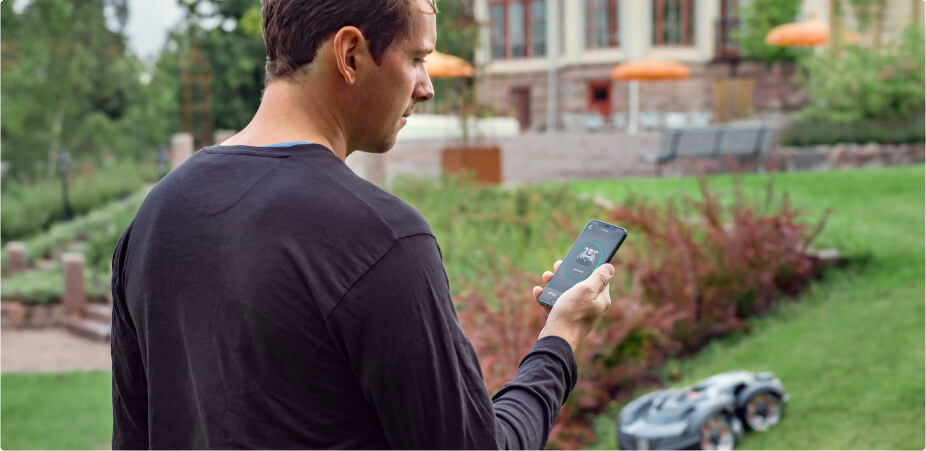Mann mit Telefon nutzt Automower Connect App