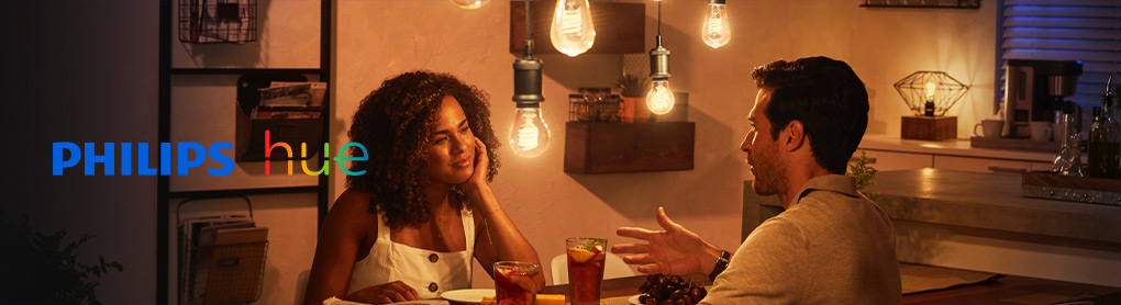 Mann und Frau am Esstisch mit gedimmten smartem Licht und Philips Hue Logo
