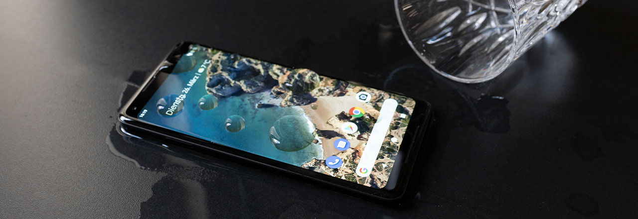 Google Pixel mit Wasser überschüttet neben umgefallenem Wasserglas