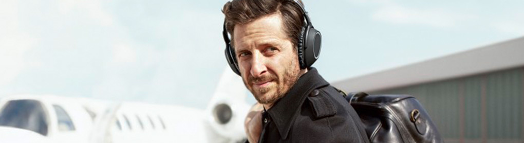Mann mit Over-Ear-Kopfhörern schaut über die Schulter am Flughafen