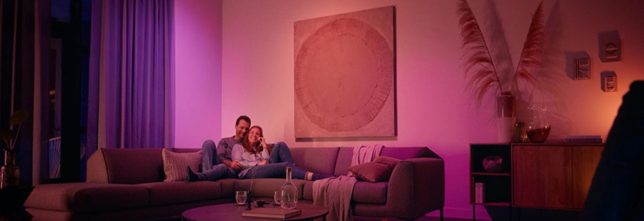 Glückliches Paar sitzt auf einem Sofa in farbigem Licht