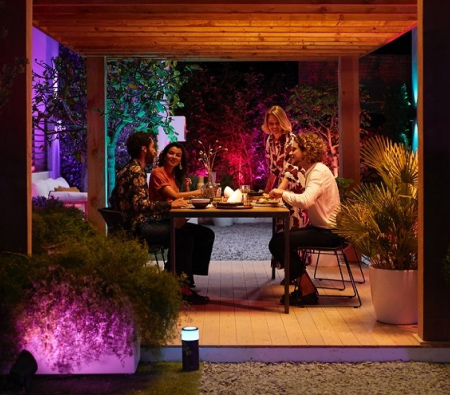 Freunde sitzen auf der Terasse mit Philips Hue Gartenbeleuchtung